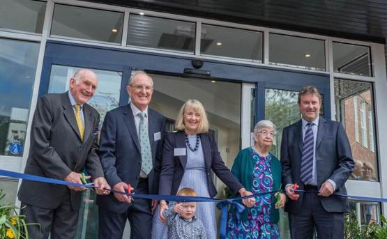 A group of people is holding a ribbon at the opening celebration of Budleigh Hub in Devon