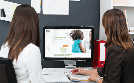 two women look at a computer screen at a desk