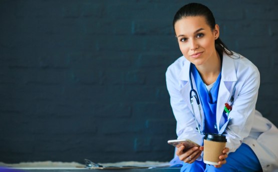 Female Doctor holding coffee cup and a smart phone 