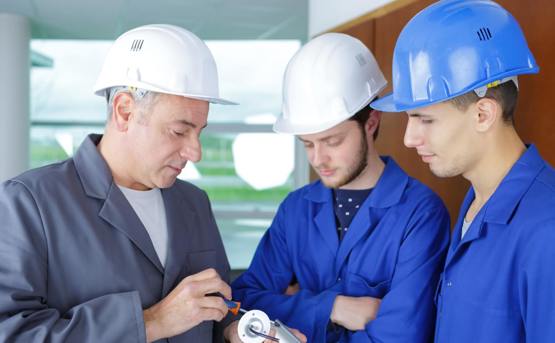 Image of electrician showing 2 apprentices how to wire light fitting