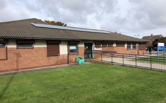 Front of a one storey health centre with lots of green grass