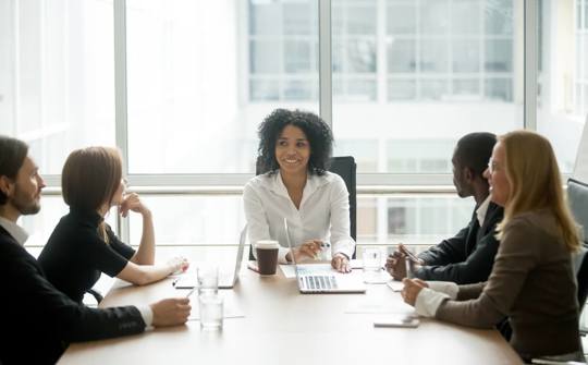 Woman Chairing Business Meeting With Four Other People Around a Table