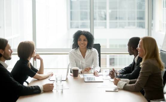 Woman Chairing Business Meeting With Four Other People Around a Table